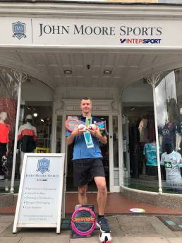 Picture of a man standing in front of John Moore Sports shop.