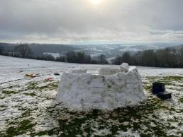 Picture of an igloo in a field.