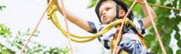 Picture of a boy doing a tree climbing challenge.