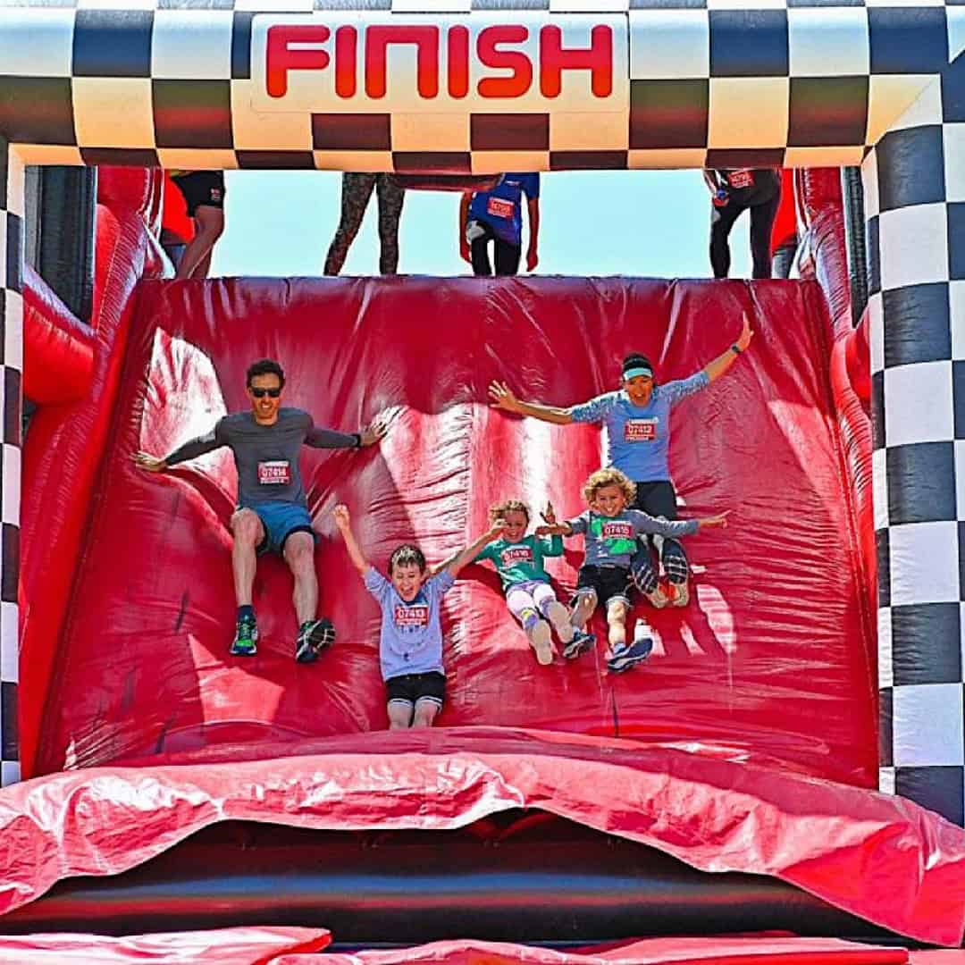 Family sliding down the finish line on a inflatable..