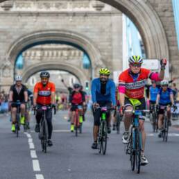 People cycling over a bridge in London.