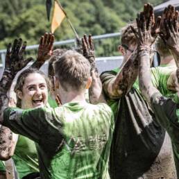 People celebrating at finish line with mud on them.