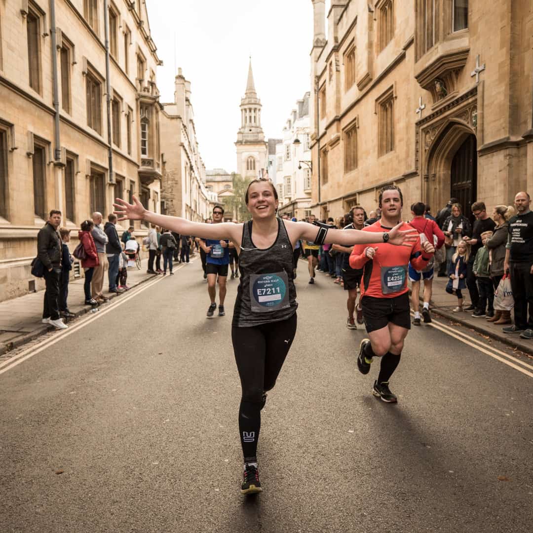 woman running down a street in Oxford celebrating