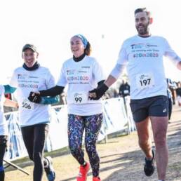 three people crossing the finish line in a 10k race.